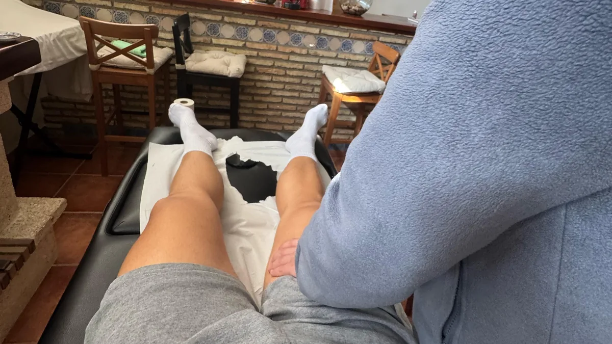 Fisioterapeuta tratando a un paciente en la camilla montada en su salón, en Córdoba